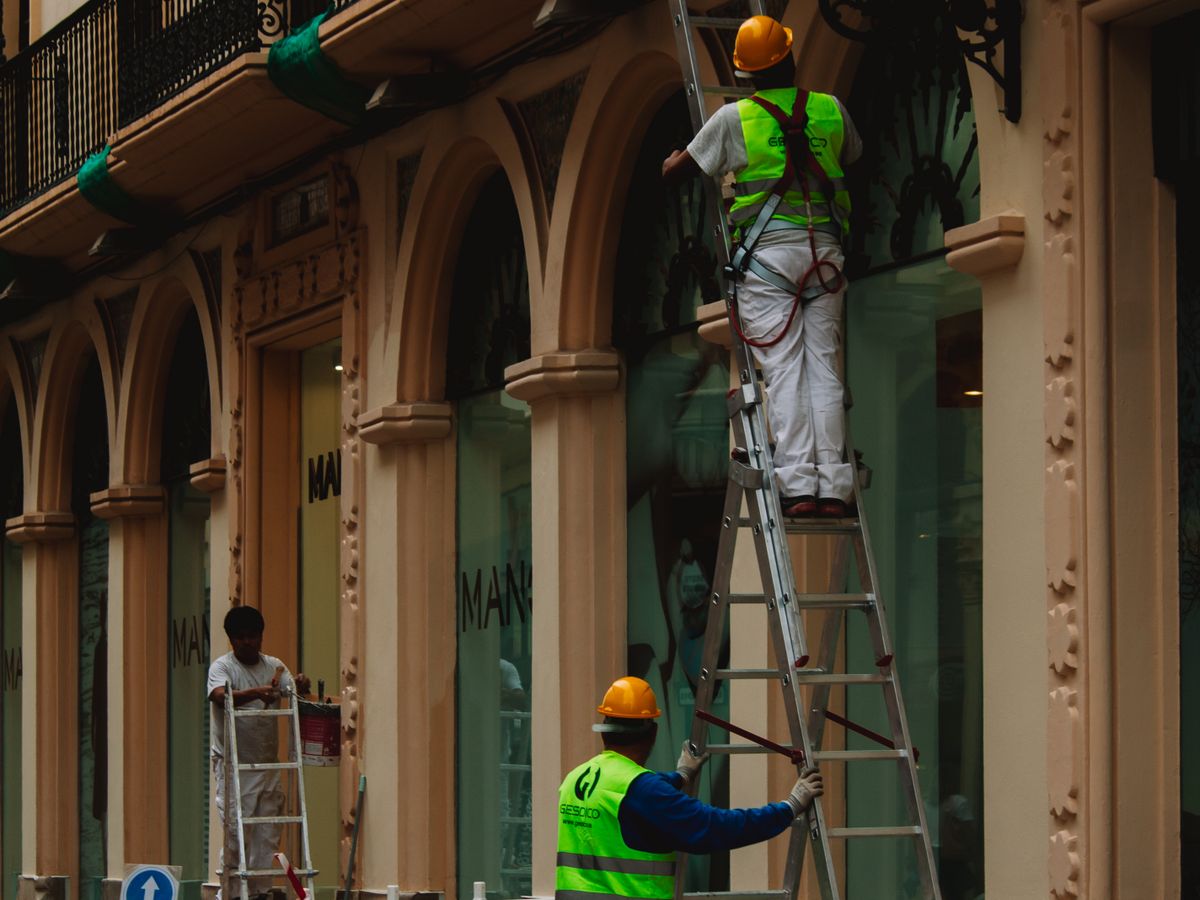 Equipe de obra com colete e capacete recuperando fachada de prédio